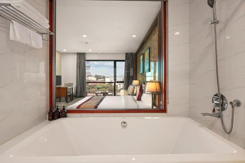 a bath tub in a bathroom with a large mirror at MT Collection Hotel in Ninh Binh