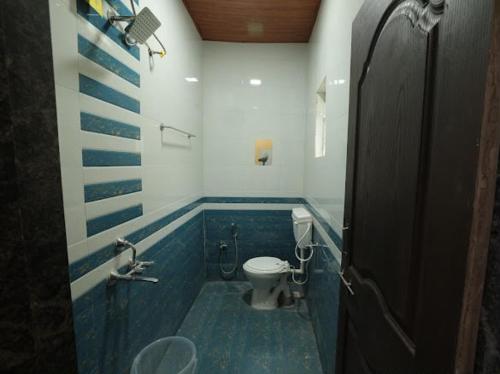 a bathroom with a toilet and a blue tile floor at Veranda hillside retreat in Kharakvasla