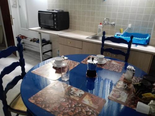 uma cozinha com uma mesa azul com cadeiras e um micro-ondas em Cosy Apartment Pinotsi em Atenas