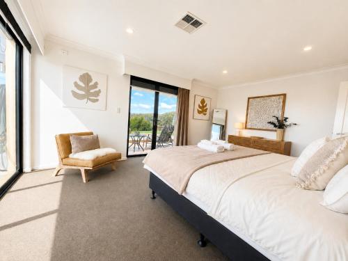 a bedroom with a large bed and a chair at Zig Zag Retreat - Hilltop Home With Stunning Views in Perth