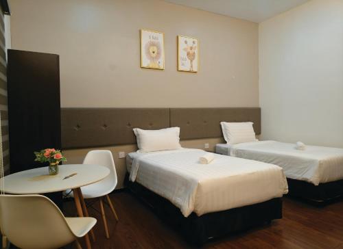 a hotel room with two beds and a table at Windsor Lane Hostel Ipoh in Ipoh