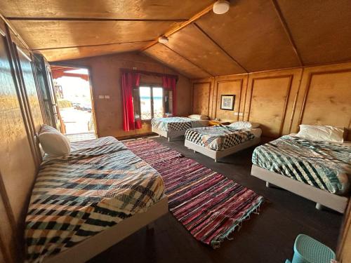 a train room with three beds and a rug at Free Beach Camp in Nuweiba‘ el Muzeinah
