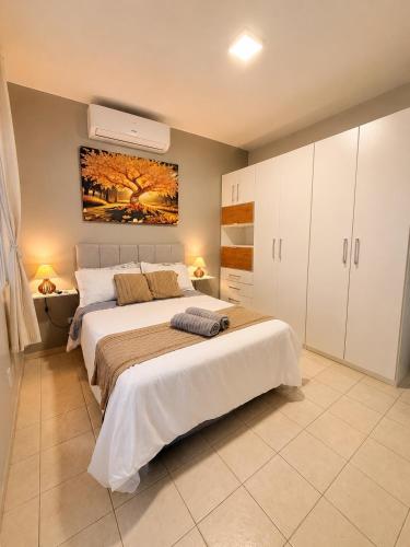 a bedroom with a large bed and a painting on the wall at Apto no centro - Praça Mini Golf - Sacada - Garagem - 300m do Mar - Térreo in Capão da Canoa