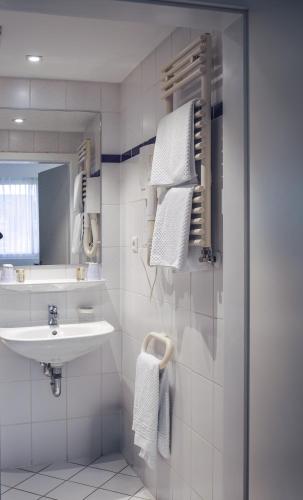 ein weißes Badezimmer mit Waschbecken und Spiegel in der Unterkunft Hotel Francais in Luxemburg (Stadt)