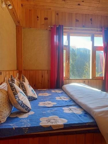 a large bed in a room with a window at Shikhar cottage in Jibhi