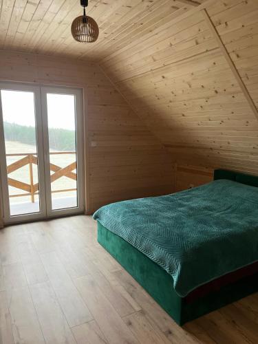 a bedroom with a green bed and a large window at Gruszchatka 1 in Gruszów