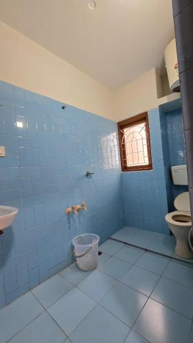 a blue tiled bathroom with a toilet and a sink at Vedhas Holidays in Kodaikānāl