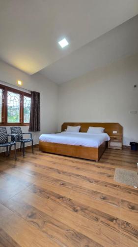 a bedroom with a large bed and wooden floors at Vedhas Holidays in Kodaikānāl