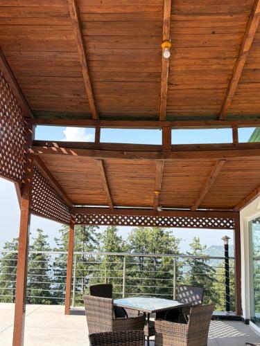 a wooden pergola with a table and chairs on a patio at Nizalia resorts in Patriata