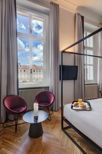 a hotel room with a bed and two chairs and a table at San Carlo Suite Torino in Turin