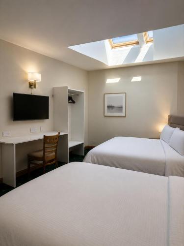 a hotel room with two beds and a desk and a television at Blue Water House in Bundoran