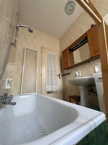a bathroom with a white tub and a sink at Appartamento Iris in Torre Pellice