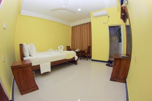 a bedroom with a bed in a room with yellow walls at Hotel Pearl Gate in Chilaw