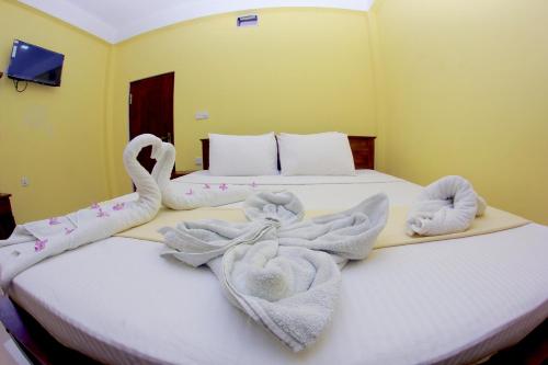 a bedroom with two swans towels on a bed at Hotel Pearl Gate in Chilaw