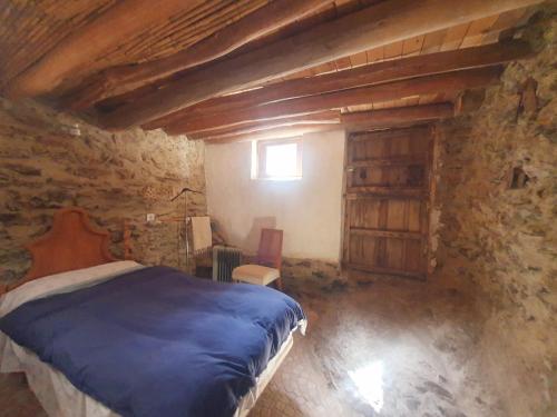 a bedroom with a bed in a stone building at Cortijo Saucillo in Albondón