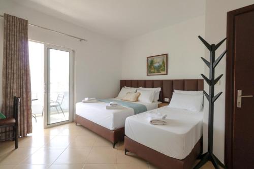 a hotel room with two beds and a balcony at Vila Enea in Ksamil