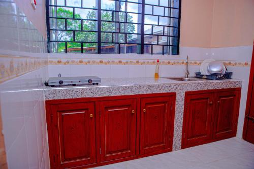 a kitchen with red cabinets and a sink and a window at Kiliheights Getaway in Sanya Chini Station