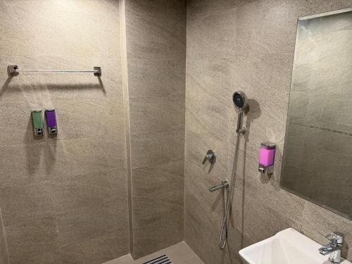 a shower with a glass door next to a sink at Luxury Swing Suite - Bliss Suites in Greater Noida