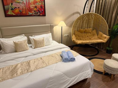 a bedroom with a wicker chair and a bed at Luxury Swing Suite - Bliss Suites in Greater Noida