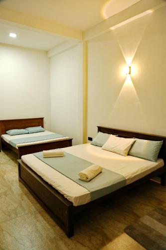 a bedroom with two beds and a light on the wall at Danu Homestay Kandy in Kandy