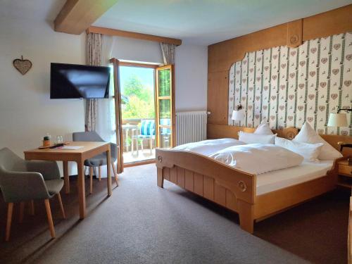 a bedroom with a bed and a desk and a television at Gästehaus Zunterer in Wallgau