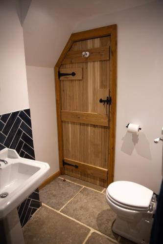 a bathroom with a toilet and a wooden door at The Old Blacksmiths in Bridgnorth