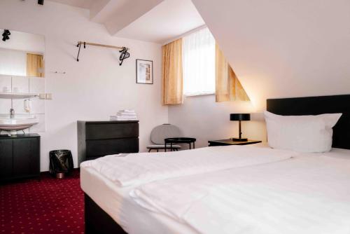a bedroom with a white bed and a sink at Landhaus Stümpelstal in Marburg an der Lahn