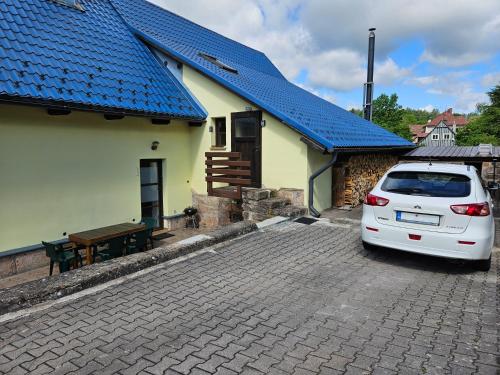 a white car parked in front of a house with a blue roof at Apartmán U Davida in Chvaleč