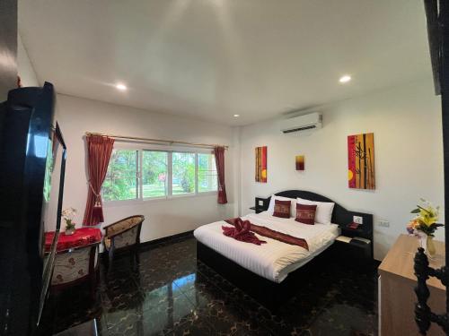 a bedroom with a large bed and a window at Ao Thai Resort in Sathing Phra