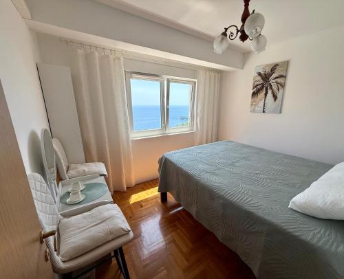 a bedroom with a bed and a chair and a window at Sea Time Apartment in Budva