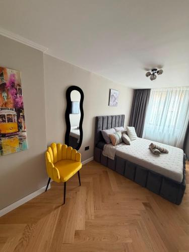 a bedroom with a bed and a yellow chair at GZP Residence Lugoj 13 in Lugoj