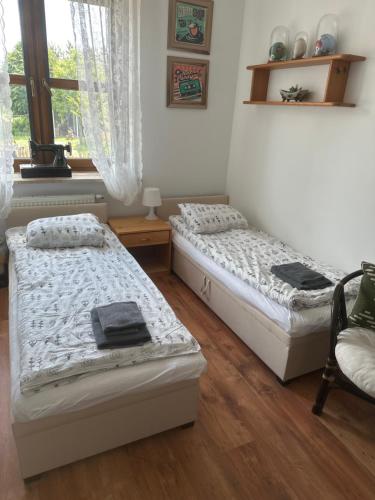 a bedroom with two beds and a chair and a window at Agroturystyka na Górce in Nowa Wies
