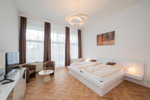 a white bedroom with a bed and a living room at Wellness Hotel Orlík in KozÃ¡rovice