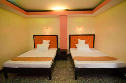 two beds in a room with yellow walls at RSG Microhotel in General Santos