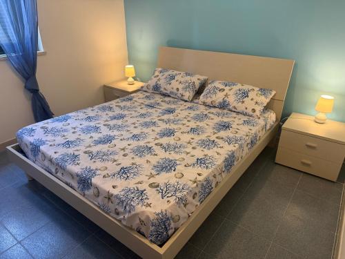 a bedroom with a bed with a blue and white comforter at Anno Zero Sweet House in Stazione di San Sostene
