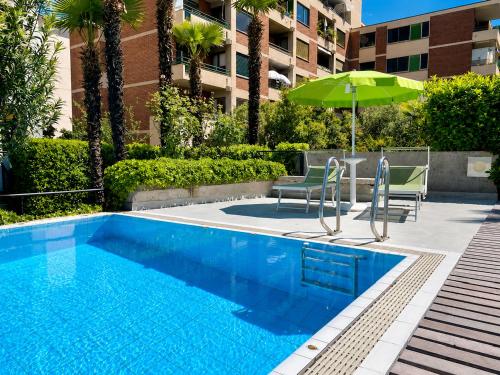 a swimming pool with two chairs and an umbrella at Hotel Nessi Locarno in Locarno