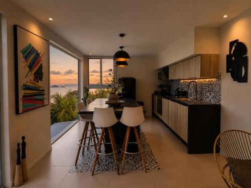 a kitchen with a large window and a table with stools at Résidence Nakiya in Sainte-Marie
