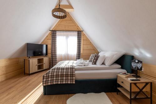 a bedroom with a bed and a television in a attic at Apartamenty Wiktorówka in Poronin