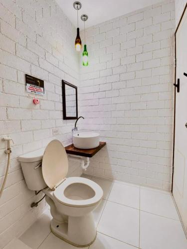 a white bathroom with a toilet and a sink at Alona Marga in Panglao Island