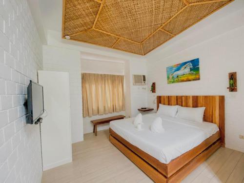 a bedroom with a large bed and a television at Alona Marga in Panglao Island
