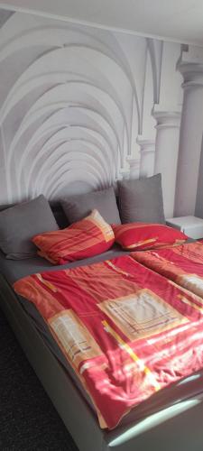 a bed with a red blanket and pillows on it at Elsternest in Neubrandenburg