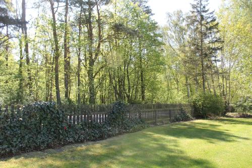 a fence in a yard with trees and grass at Kärraton Stugor in Åhus
