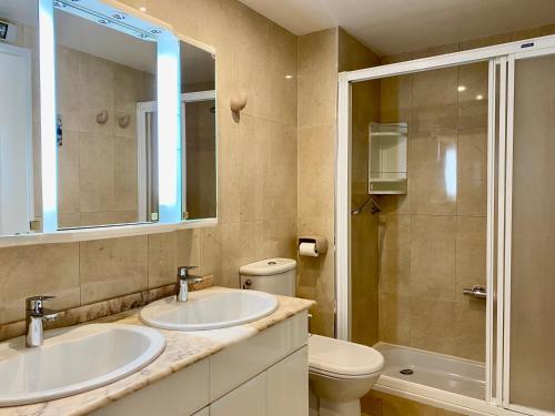 a bathroom with two sinks and a toilet and a shower at Luxurious apartment seafront Moraira by Moraira Holiday Homes in Moraira