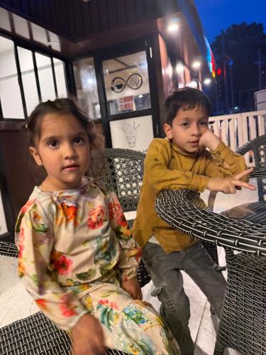 two young children sitting on chairs in front of a store at Himalayan Stay in Sonāmarg