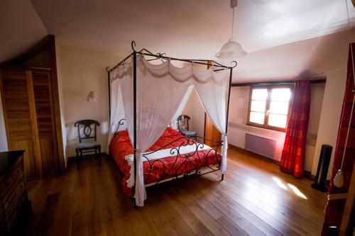 a bedroom with a canopy bed and a wooden floor at Le Clos de La Réserve in Cinq-Mars-la-Pile