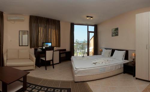 a hotel room with a large bed and a desk at Hotel Vemara Club in Byala