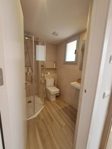 a bathroom with a toilet and a glass shower at Aparthotel ALMARIS in Es Pujols