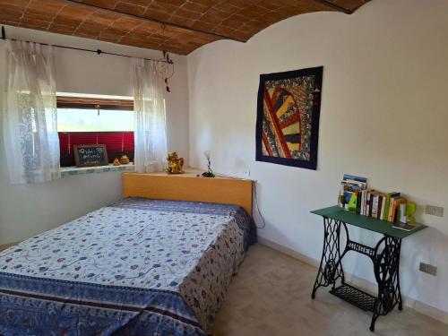 a bedroom with a bed and a table and a window at Cascina E&E in Costigliole dʼAsti