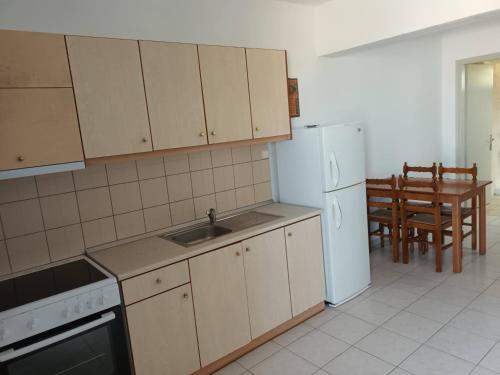 a kitchen with a sink and a refrigerator and a table at Panorama Apartment 1 in Moúdhros