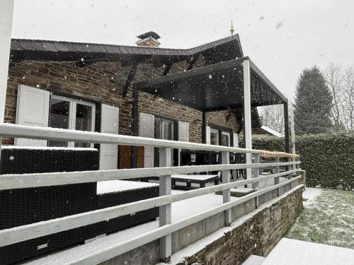 a house covered in snow in front of a building at La Semois Et Moi in Rochehaut
